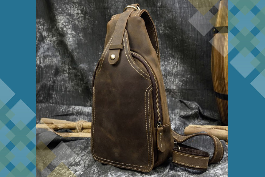 Brown leather sling bag on a textured surface with a blurred background