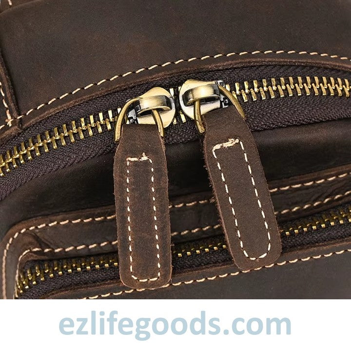 Close-up of a dark brown leather bag with gold zipper and stitching detail, featuring the brand 'ezlifegoods.com'.